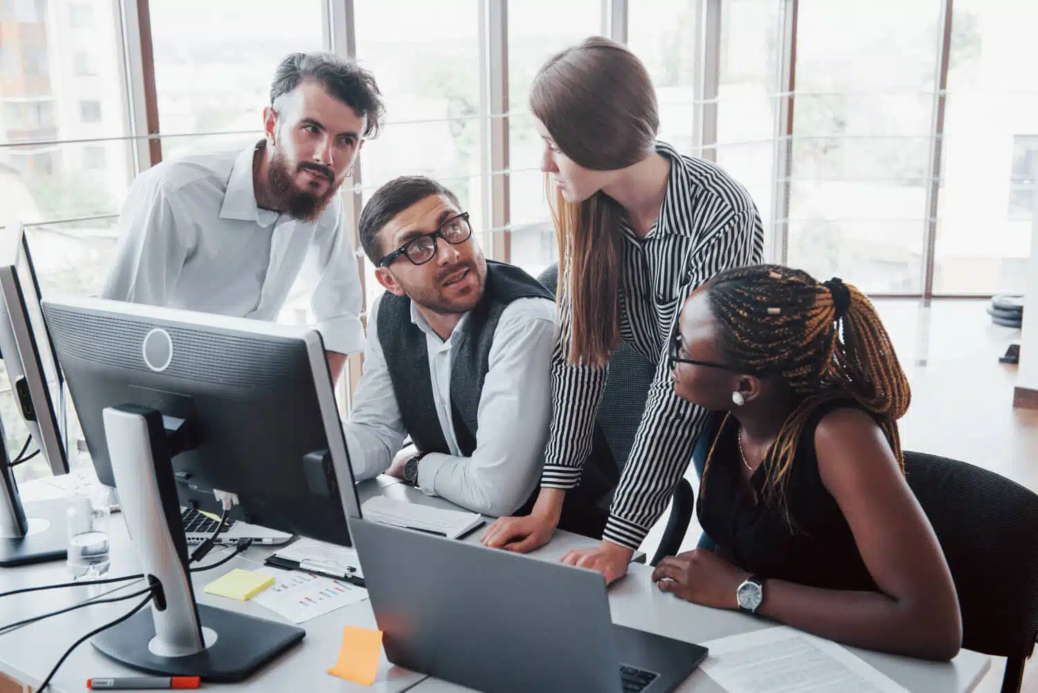 Programação e liderança - uma pessoa trabalhando em um computador e liderando uma equipe de desenvolvedores em uma sala de reuniões