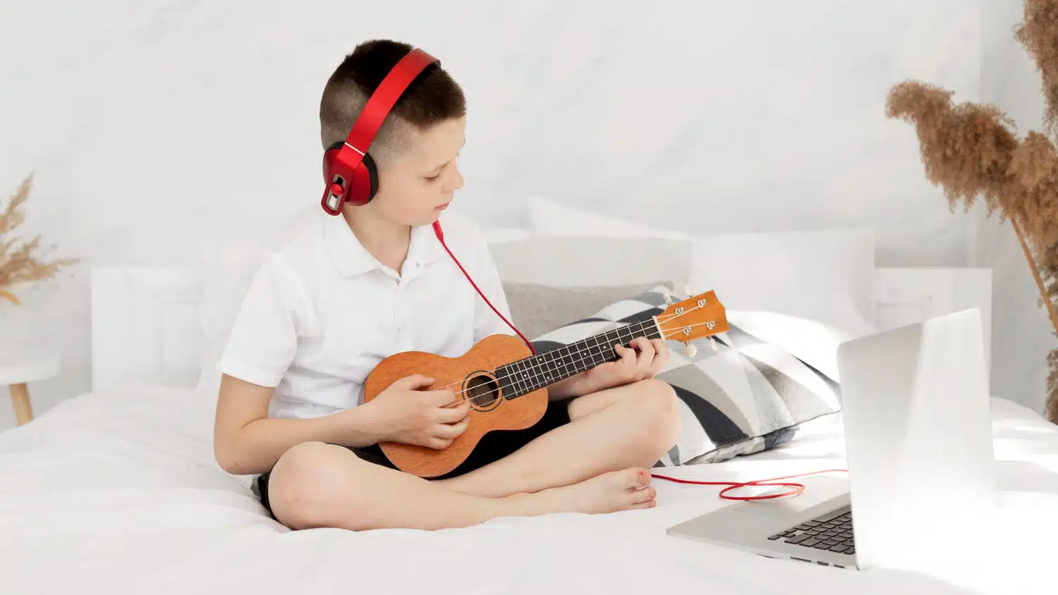 Uma criança tocando um instrumento musical com um laptop aberto mostrando código de programação ao lado